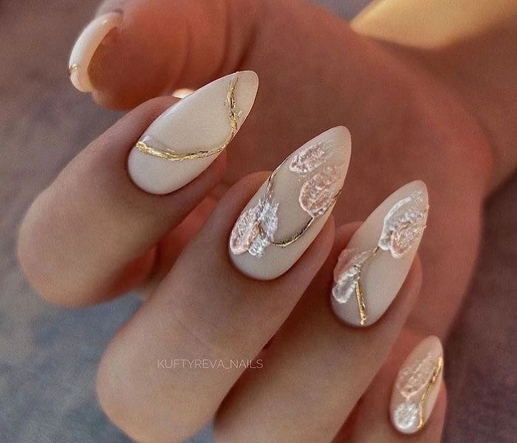 Elegant almond-shaped nails featuring a soft beige base with delicate gold foil accents creating a luxurious and sophisticated manicure.