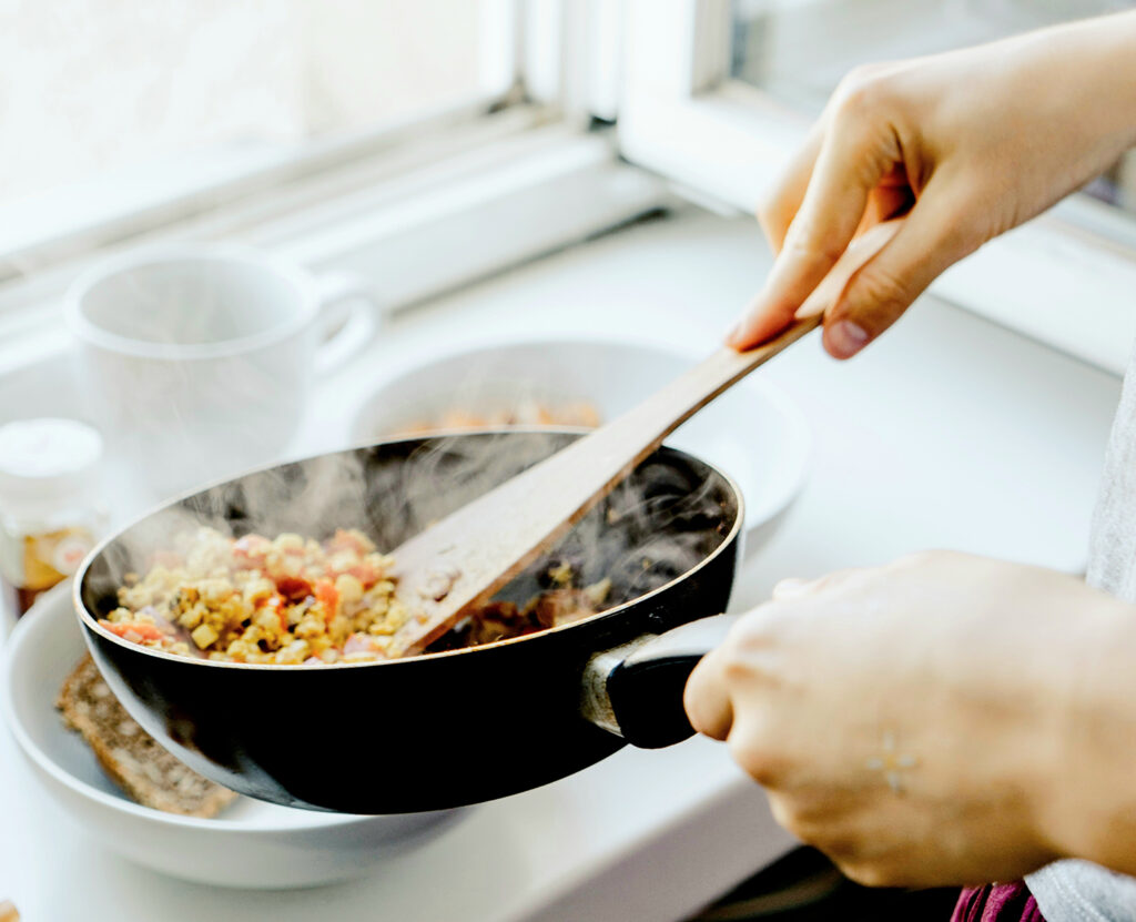 Cooking up a delicious meal in a frying pan on a stovetop, with steam rising from the sizzling food.
