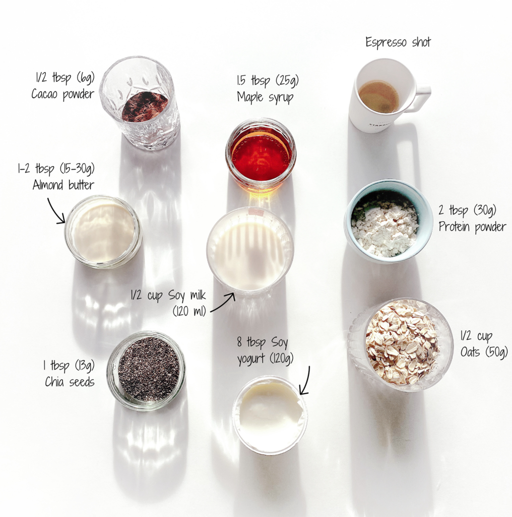 An assortment of ingredients neatly organized and labeled for a high protein, vegan tiramisu overnight oats recipe, including cacao powder, almond butter, maple syrup, espresso shot, protein powder, chia seeds