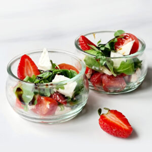 Two glass bowls with fresh Strawberry Spring Salad containing strawberries, arugula, and feta cheese